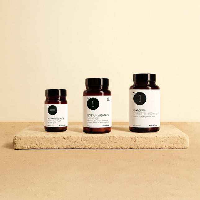 Das Menobalance-Set von Medicom mit 3 Produkten für die Frau: Vitamin D3+K2 Tabletten, Nobilin Woman Balance und Calcium Tabletten 600 mg auf einem Steintablett